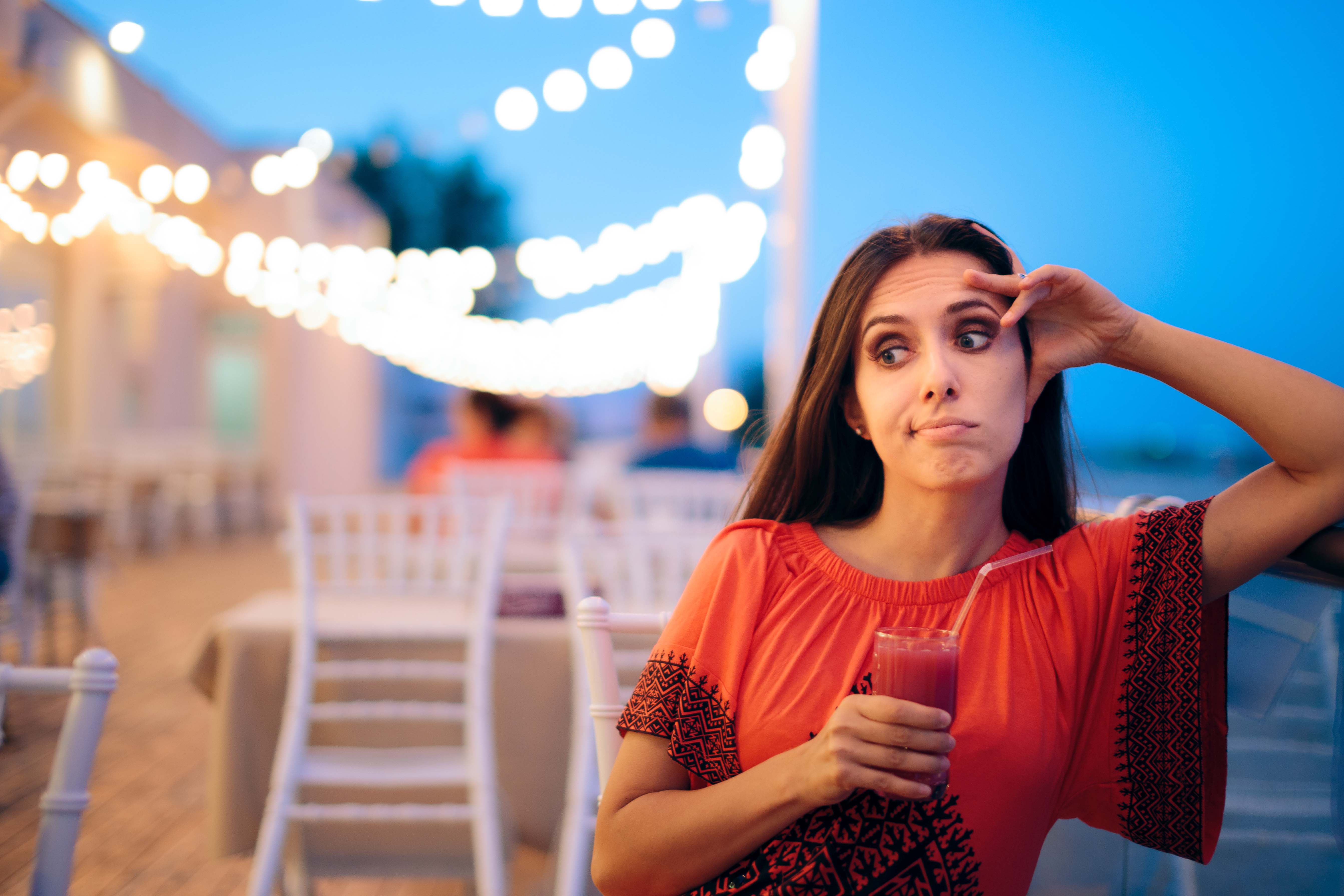 Woman with a drink contemplating how to respond to an awkward dating question.