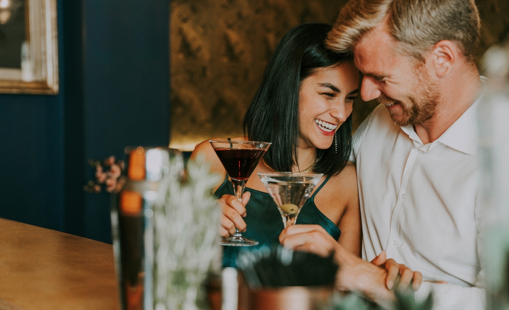 Happy couple on a date at a bar with a women smiling